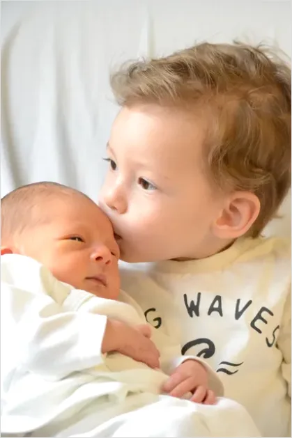 Detail New Big Sibling Holding Newborn Gently Number 2